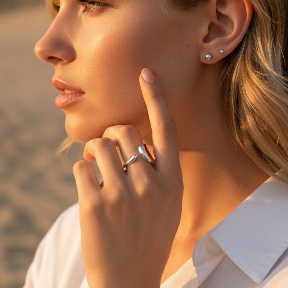 Bague NAMI portée à l'annulaire par une femme, illustrant son style fluide et son éclat solaire sous une lumière naturelle.