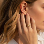 Bague NAMI portée à l'annulaire par une femme, illustrant son style fluide et son éclat solaire sous une lumière naturelle.