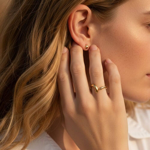 Bague NAMI portée à l'annulaire par une femme, illustrant son style fluide et son éclat solaire sous une lumière naturelle.