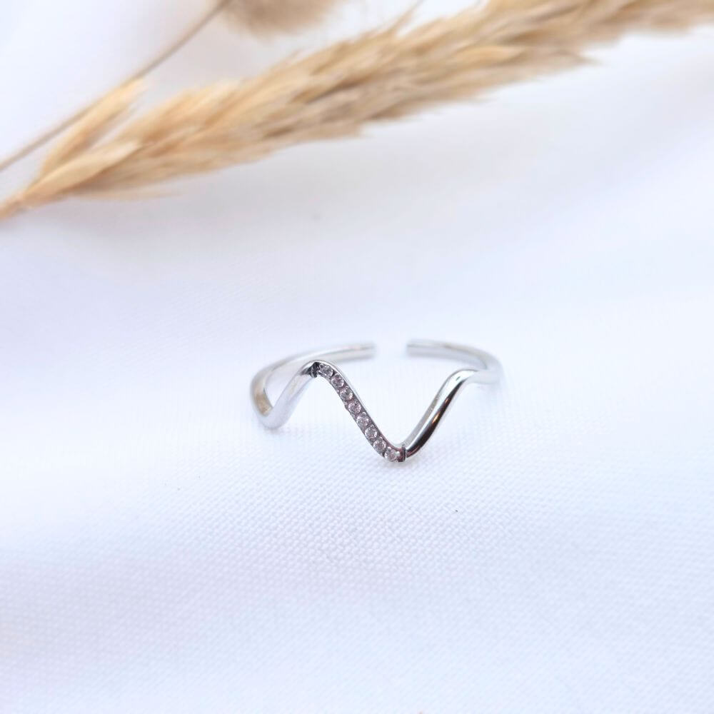 Bague PURE minimaliste en acier inoxydable, design anneau lisse et épuré, posée sur un tissu blanc avec un épi de blé séché.