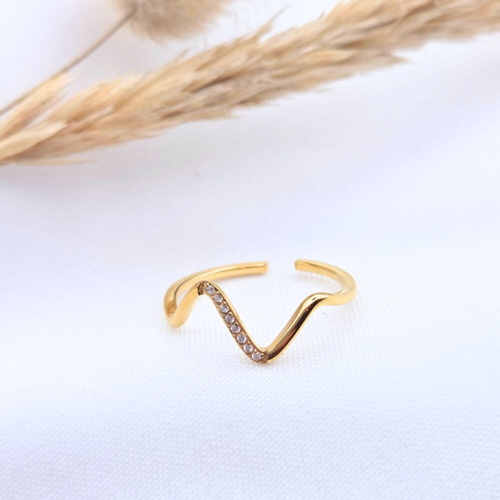 Bague PURE minimaliste en acier inoxydable doré, design anneau lisse et épuré, posée sur un tissu blanc avec un épi de blé séché.