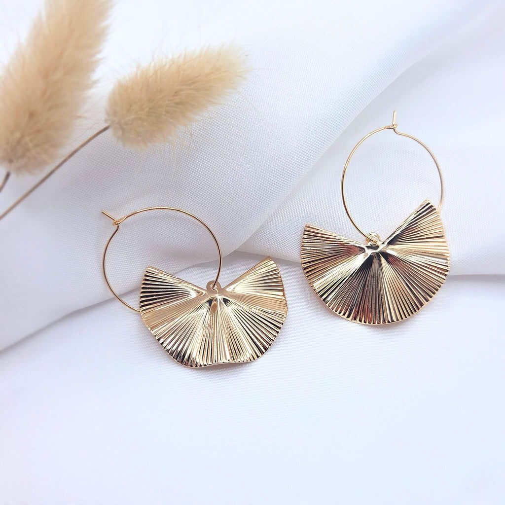Créoles dorées avec pendentifs demi-lune texturés de style éventail sur fond blanc élégant.