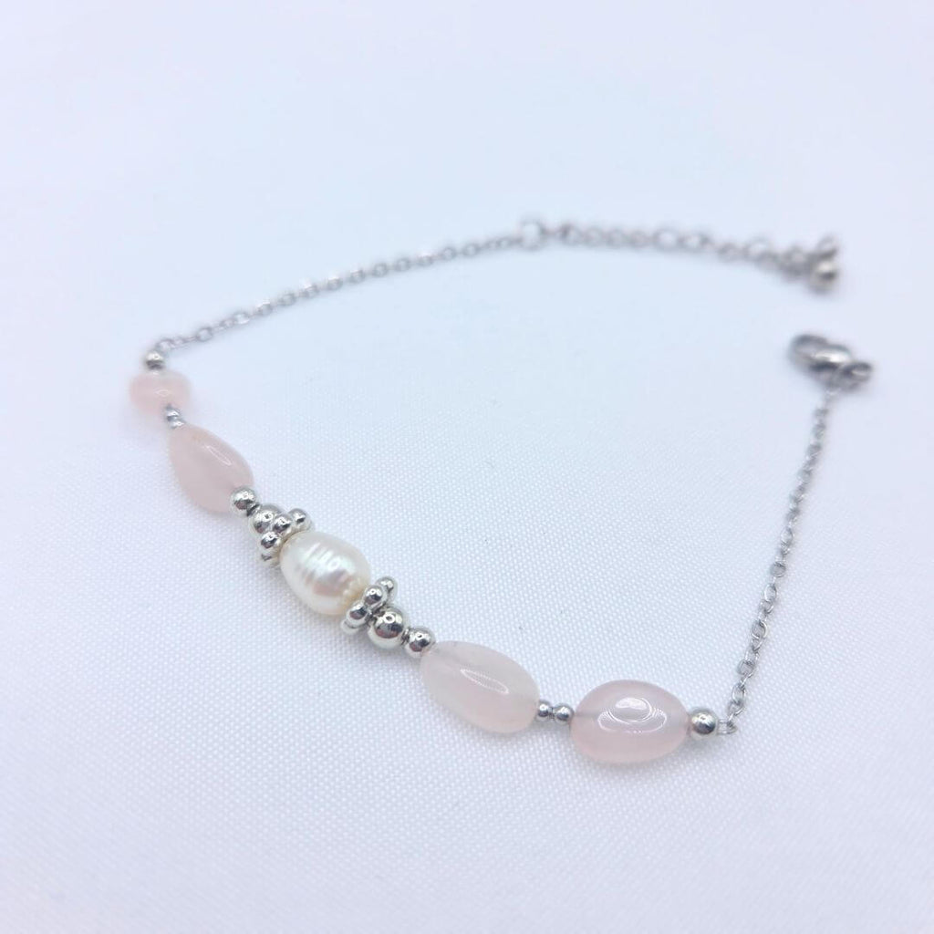 Bracelet NATTY en argent avec perles de quartz rose et perle d'eau douce centrale posé à plat.