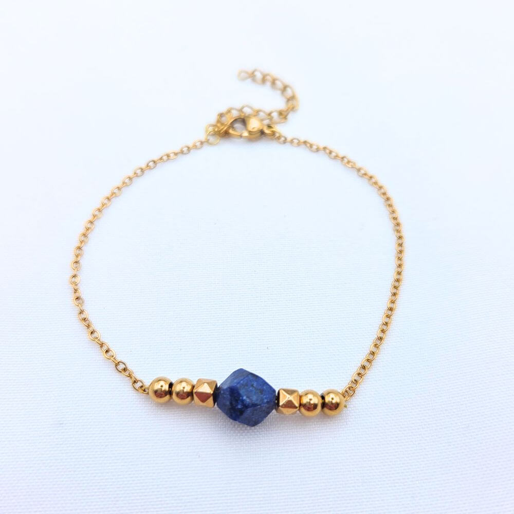 Bracelet fin en chaîne dorée avec une pierre centrale en Lapis-lazuli bleu brut et perles dorées géométriques.