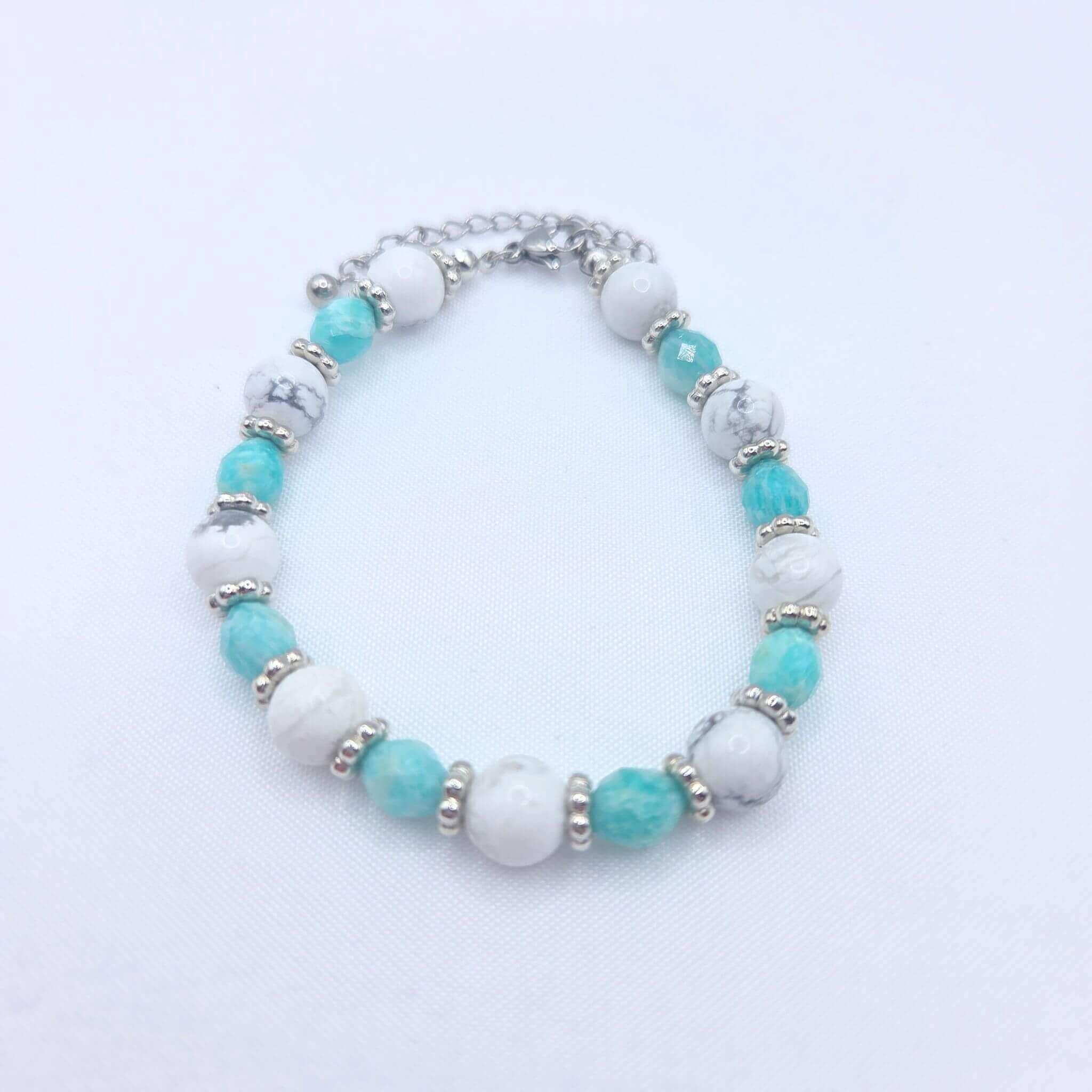 Gros plan du poignet d'une femme portant le bracelet GIA de M-ily Glow Up sous une lumière naturelle. Le bijou alterne des perles de Howlite blanche et d'Amazonite turquoise avec des séparateurs argentés.