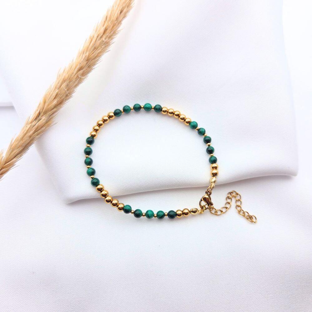 Bracelet fin en perles de malachite verte et billes dorées avec fermoir ajustable.