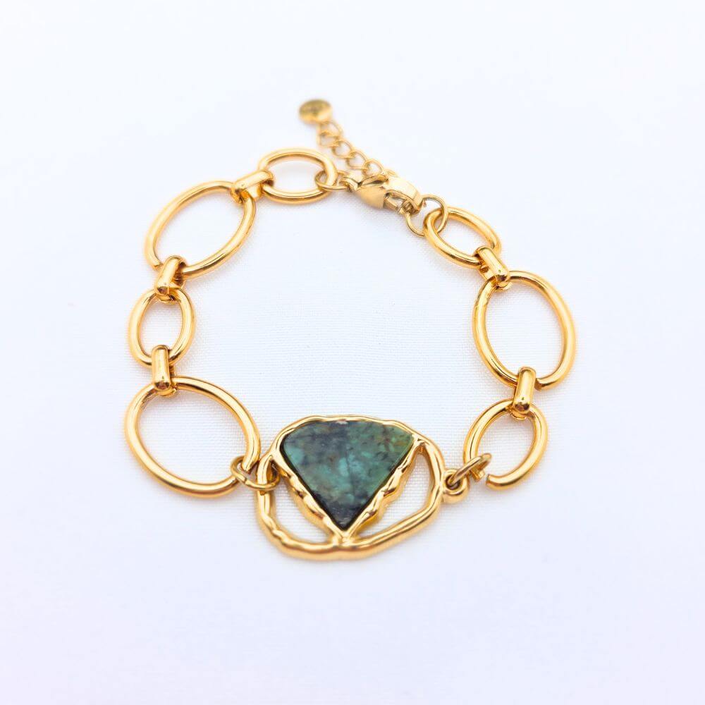 Bracelet Sélène en acier inoxydable doré avec une pierre naturelle turquoise africaine taillée en triangle, vue de dessus sur fond blanc.