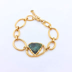 Bracelet Sélène en acier inoxydable doré avec une pierre naturelle turquoise africaine taillée en triangle, vue de dessus sur fond blanc.