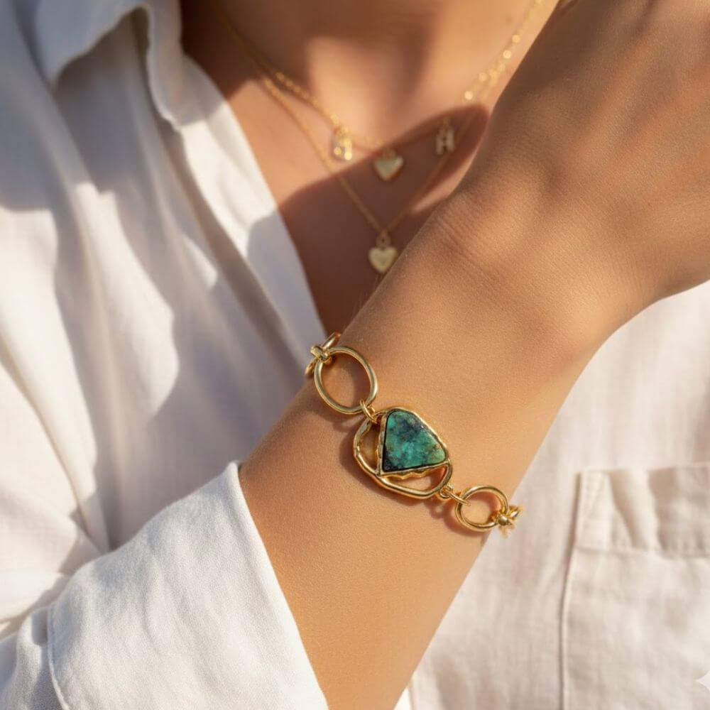 Gros plan du bracelet Sélène porté au poignet d'une femme, mettant en valeur la pierre turquoise africaine et les maillons dorés sous une lumière naturelle chaude.