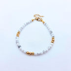 Bracelet fin en perles de Howlite blanche marbrée et détails dorés, fermoir mousqueton ajustable.