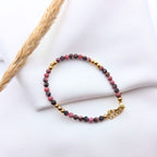 Bracelet fin en perles de Rhodonite rose et noire avec détails et fermoir dorés.
