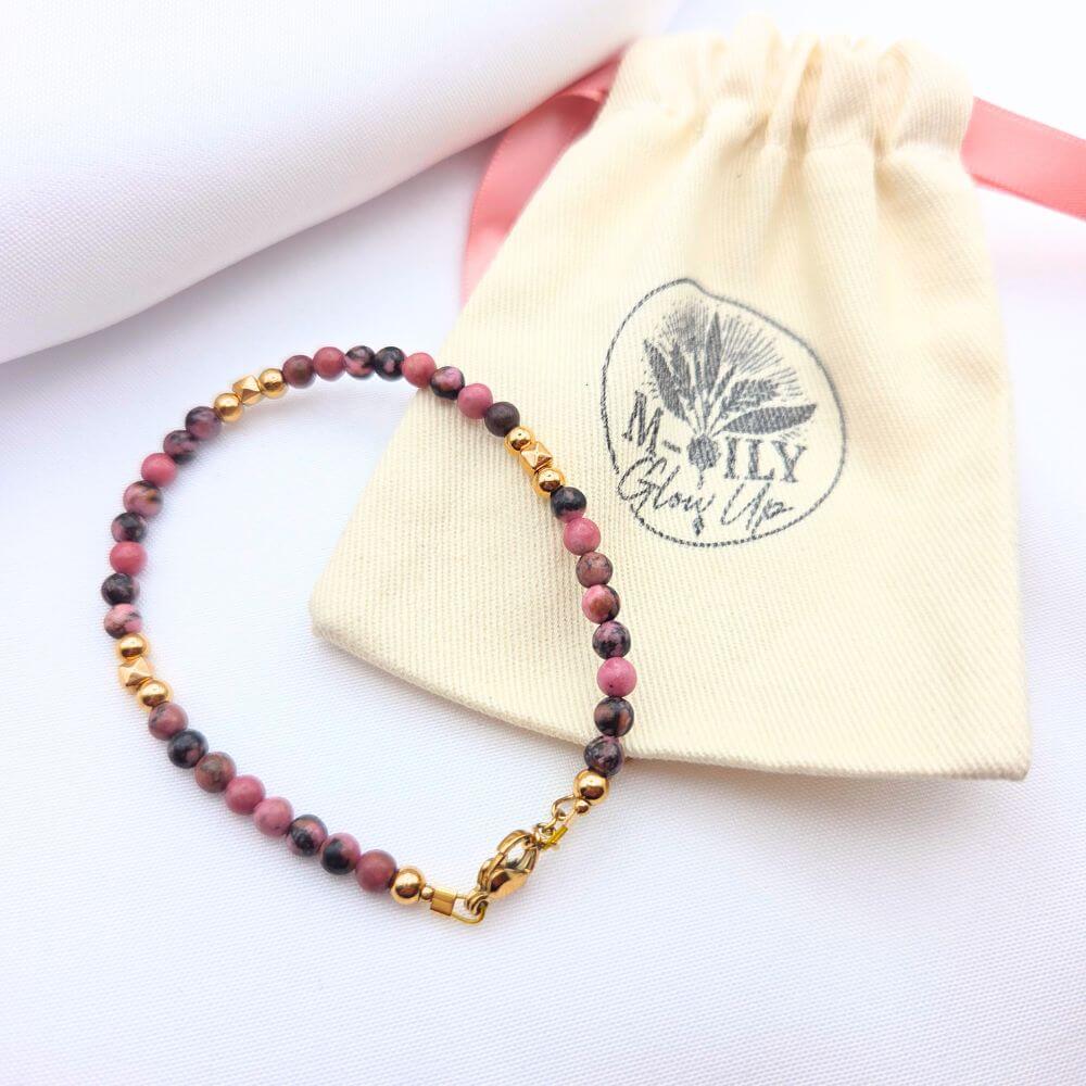 Bracelet en perles de Rhodonite rose et noire avec détails dorés et pochon en coton M-ily Glow Up.
