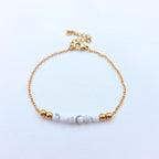 Bracelet fin en chaîne dorée orné de perles de howlite blanche marbrée et de perles d'acier inoxydable dorées.