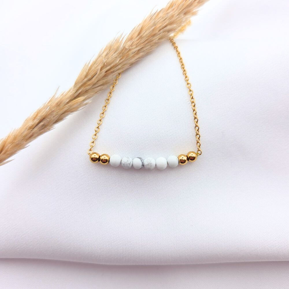 Bracelet fin en chaîne dorée avec perles de howlite blanche et billes d'or.
