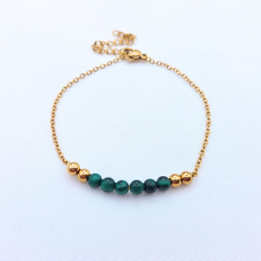 Bracelet fin en maille dorée orné de perles de malachite vertes et de billes dorées.