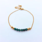 Bracelet fin en maille dorée orné de perles de malachite vertes et de billes dorées.