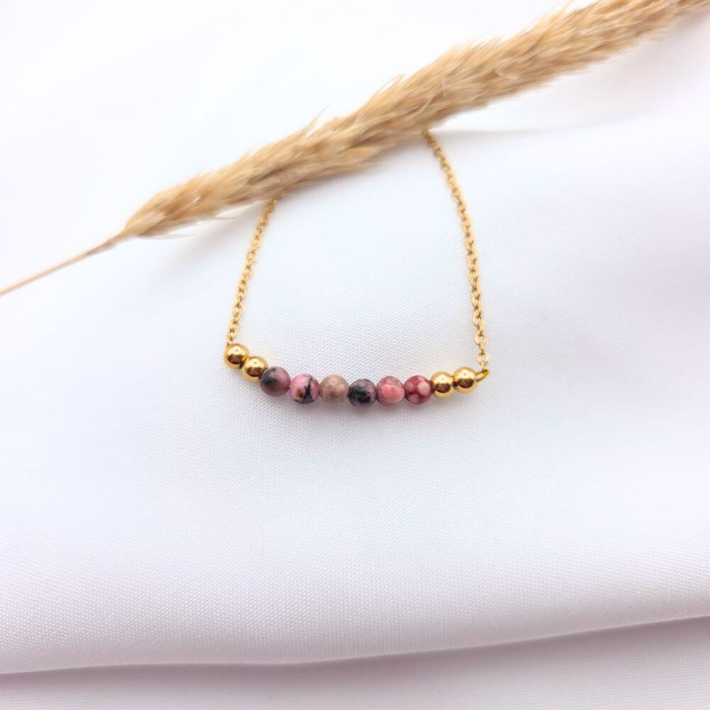 Collier en chaîne dorée fine orné d'une barre de perles naturelles en rhodonite rose et noire.