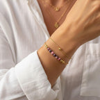 Femme portant un duo de bracelets dorés avec perles en pierre naturelle rose marbrée sur un chemisier blanc.