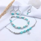 Parure de bijoux artisanaux M-ily Glow Up collection GIA incluant un bracelet, un collier avec pendentif fleur et des boucles d'oreilles en howlite blanche et amazonite.
