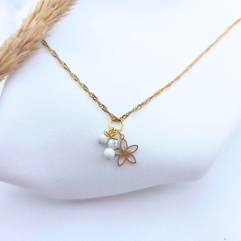 Collier doré en maille torsadée avec pendentif fleur évidée et perles blanches marbrées en Howlite.