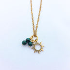 Collier en chaîne torsadée dorée avec pendentif soleil évidé et trois perles de malachite verte.