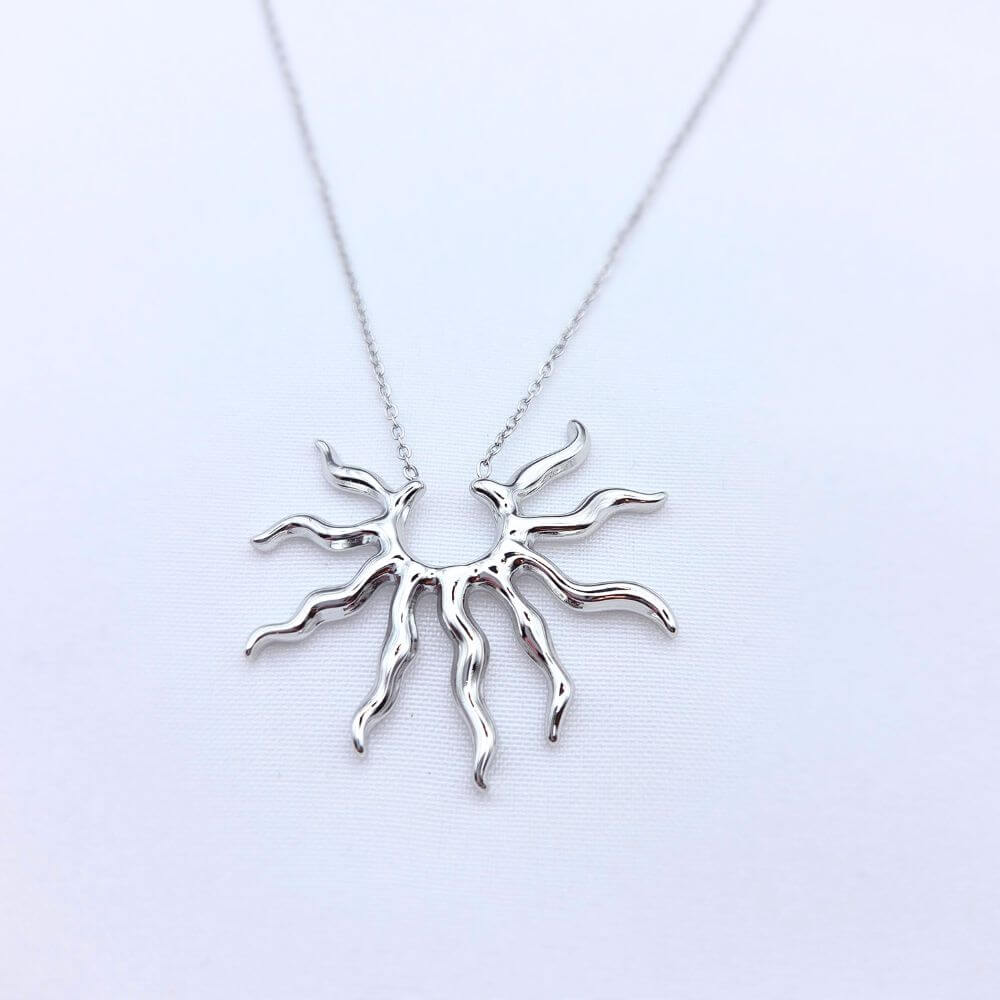 Vue rapprochée du collier MIMOSA montrant les détails de la médaille texturée et la finesse de la chaîne en acier inoxydable doré sur fond blanc.