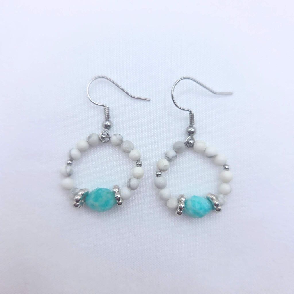Paire de boucles d'oreilles créoles GIA en pierres naturelles, composées de perles de howlite blanche marbrée et d'une perle centrale en amazonite turquoise facettée sur un fond blanc épuré.