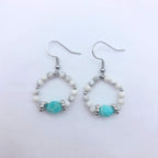 Paire de boucles d'oreilles créoles GIA en pierres naturelles, composées de perles de howlite blanche marbrée et d'une perle centrale en amazonite turquoise facettée sur un fond blanc épuré.