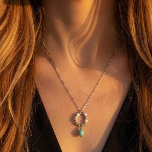 Collier avec pendentif GIA en Howlite et Amazonite porté au cou, mettant en avant la longueur de la chaîne argentée et le contraste des pierres naturelles sur la peau sous une lumière chaude.