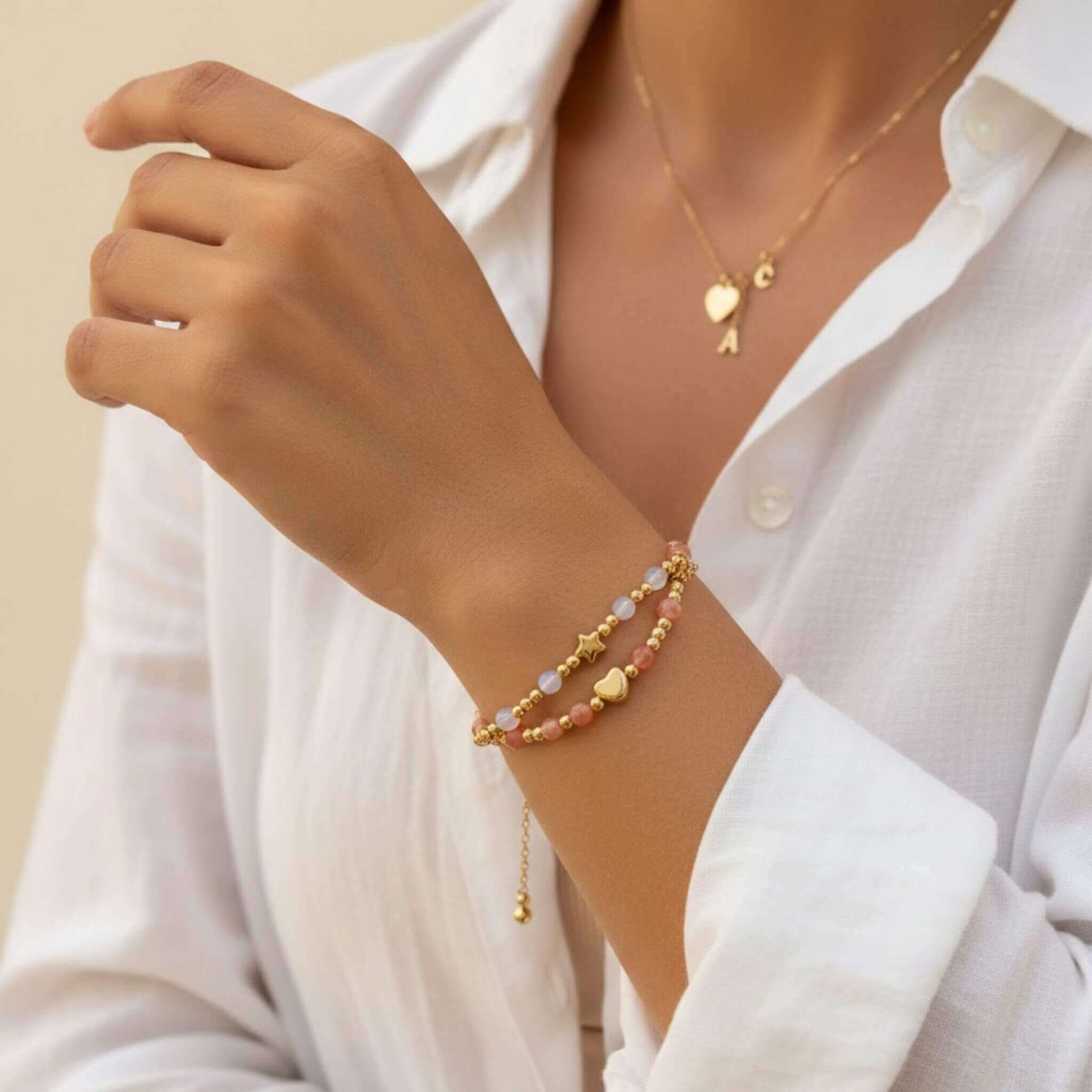 Femme portant le bracelet double rang Debbie de la marque M-ily Glow Up en pierre de soleil et pierre de lune avec charms cœur et étoile dorés.